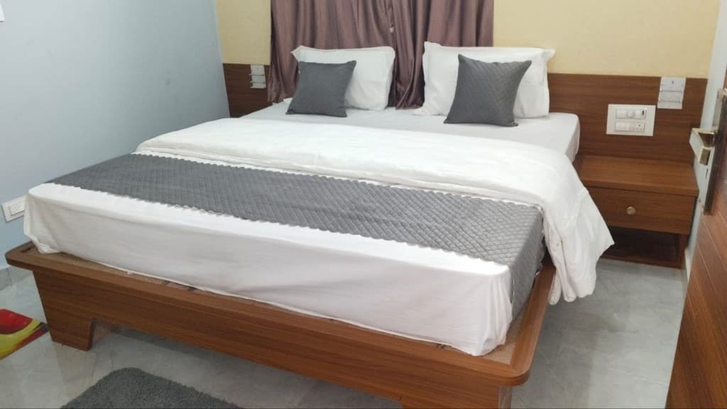 Double Room (AC) master bed setup with wooden frame and grey runners